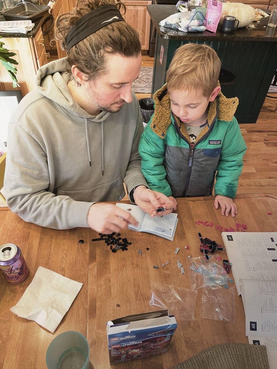 A father and his young son building a Lego set together at a kitchen table